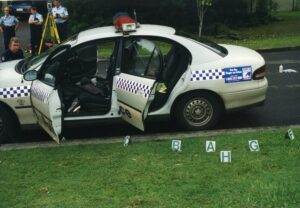 Polcie vehicle with doors open and letters indicating where the expended rifle shells lay