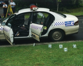 Polcie Vehicle With Doors Open And Letters Indicating Where The Expended Rifle Shells Lay