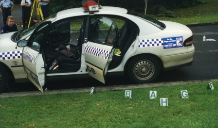Polcie Vehicle With Doors Open And Letters Indicating Where The Expended Rifle Shells Lay