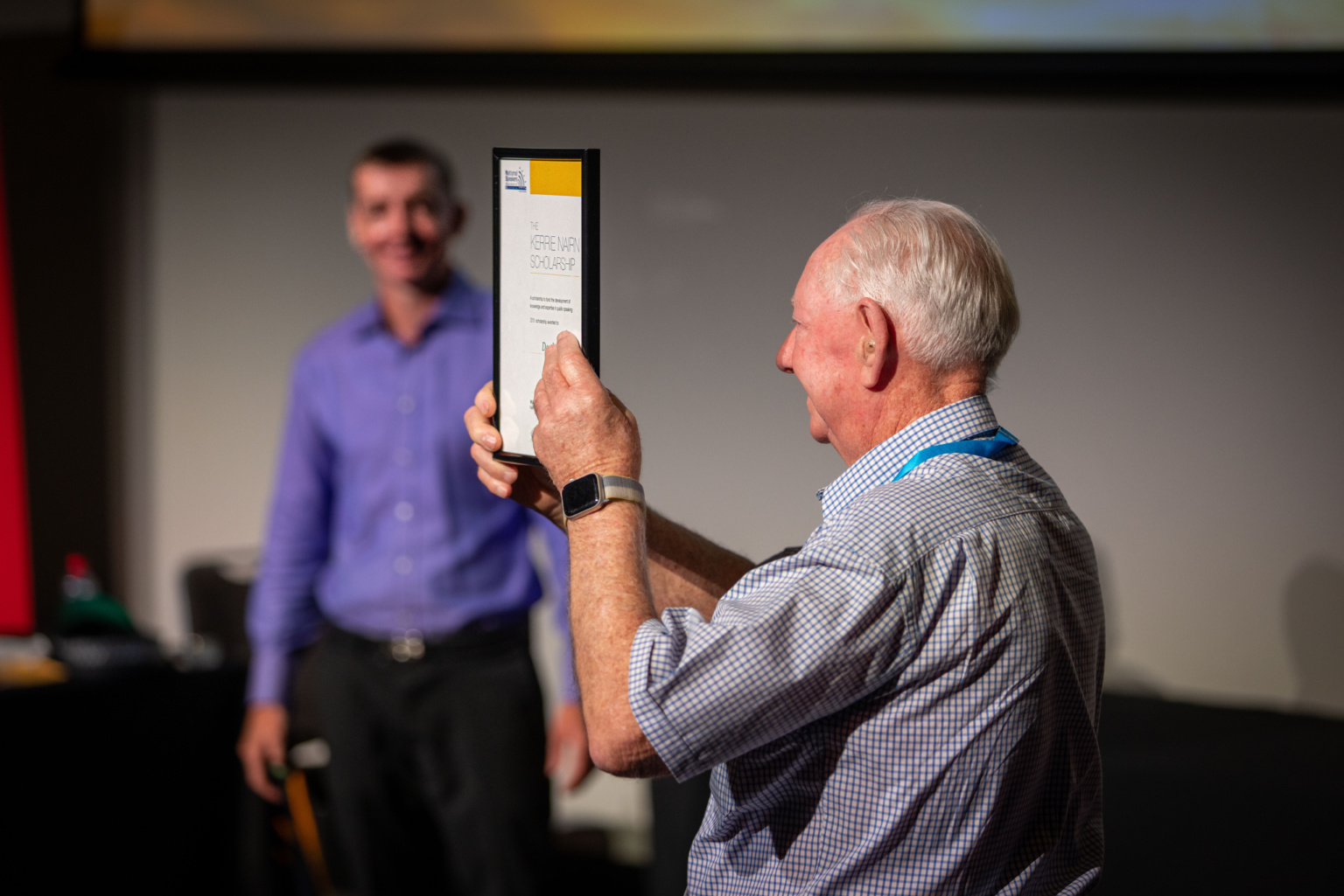 A Proud Alan Green Showing The Itsmf 2023 Conference Audience Professional Speakers Australia Kerrie Nairn Scholarship Plaque Awarded To Daryl To Help Develop Him From An Emerging Speaker To Today As A Now Full Time Professional Speaker.