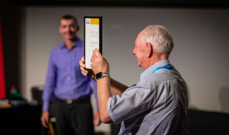 A Proud Alan Green Showing The Itsmf 2023 Conference Audience Professional Speakers Australia Kerrie Nairn Scholarship Plaque Awarded To Daryl To Help Develop Him From An Emerging Speaker To Today As A Now Full Time Professional Speaker.